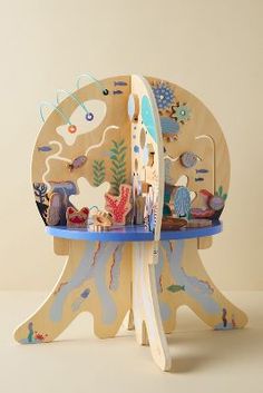 an elephant shaped wooden chair with sea creatures on it's back and legs, sitting on a blue table