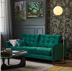 a living room with green couches and wallpaper on the walls, coffee table and lamp