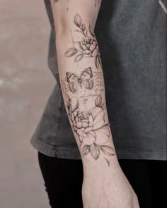 a woman's arm with flowers and butterflies tattooed on the left side of her arm