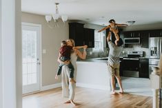 three people standing in a kitchen while one person is holding a child on his shoulders