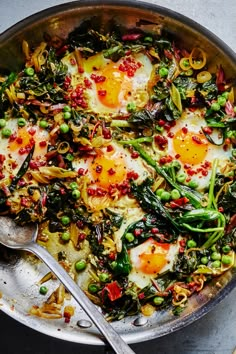 an egg and vegetable dish in a skillet with two spoons on the side