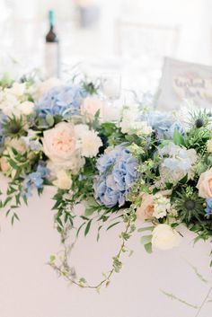 blue and white flowers are arranged on the table for an elegant centerpiece at this wedding reception