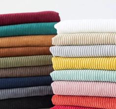 a stack of folded clothes on top of each other in different colors and sizes,