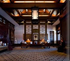 a living room filled with lots of furniture next to a tall wooden ceiling mounted light