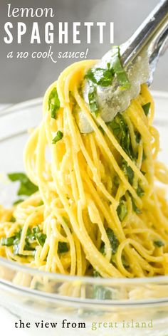 a fork full of spaghetti with parsley and cheese in a glass bowl on a white table