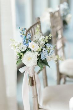 a bouquet of white and blue flowers in a vase on a chair with a bow