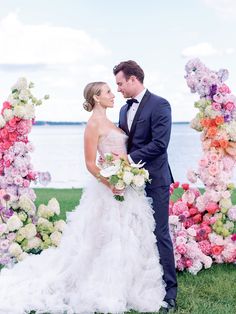 a bride and groom standing next to each other in front of an arch of flowers