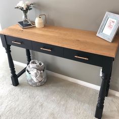 a wooden table with two drawers and a vase sitting on the floor next to it