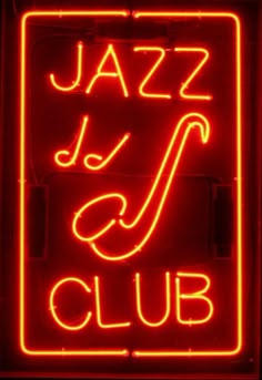 a red neon sign with the word jazz club written in white on it's side