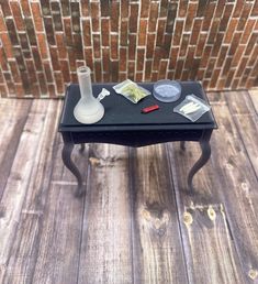 a small black table with some items on it and a brick wall in the background