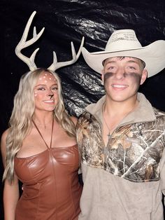 a man and woman wearing deer antlers on their heads pose for a photo in front of a black backdrop