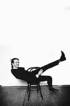 a man in a suit sitting on a chair with his legs crossed and feet up