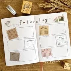 an open planner book sitting on top of a wooden table next to some rubber stamps