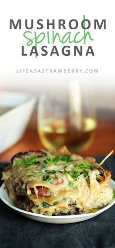 mushroom spinach lasagna on a white plate with a glass of wine in the background