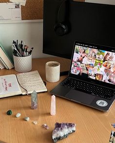 an open laptop computer sitting on top of a wooden desk next to a pile of rocks