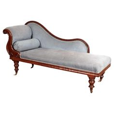 an old style chaise lounge with blue upholstered fabric and wood trimming