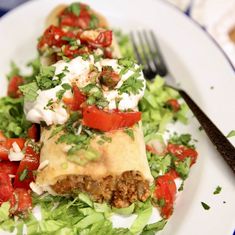 a white plate topped with meat and veggies next to a knife and fork