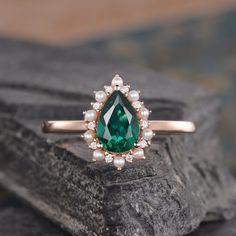 an emerald and pearl ring on top of a rock