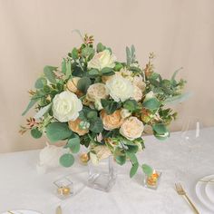 a vase filled with lots of flowers on top of a white tablecloth covered table