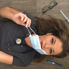 a woman with a medical mask and stethoscope laying on the floor next to her