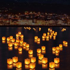 many lanterns floating in the water at night