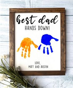 the best dad hand print is displayed in a wooden frame on a white table with flowers