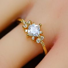 a woman's gold ring with an aqua blue stone surrounded by small white diamonds