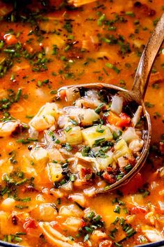 a ladle full of soup is being held by a wooden spoon