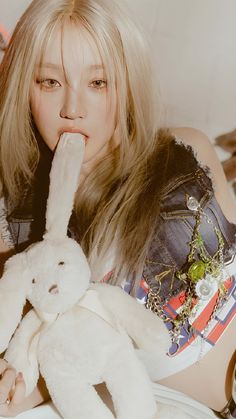 a woman laying on top of a bed next to a white bunny rabbit stuffed animal