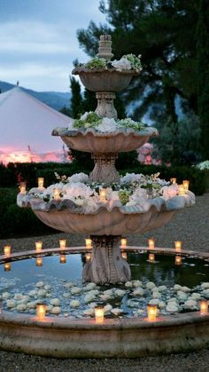 an outdoor fountain with candles and flowers on it