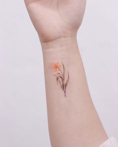 a woman's wrist with a small flower tattoo on the left side of her arm