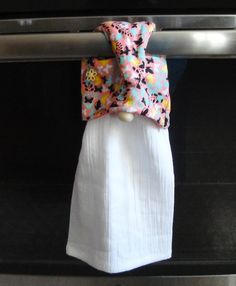 a towel hanging on the handle of an oven door with a flowered bow tie