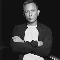 a man with his arms crossed posing for a black and white photo