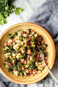 a bowl filled with beans and broccoli on top of a table