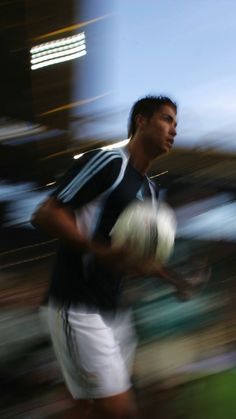 a blurry photo of a man holding a soccer ball in his right hand and running