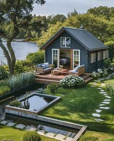 a small blue house sitting on top of a lush green field next to a lake