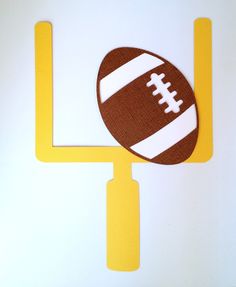 a paper cutout of a football sitting on top of a yellow pole with a white stripe