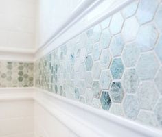 a bathroom with blue and green tiles on the wall next to a shower head mounted faucet