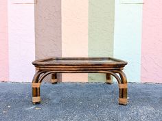 a small wooden table sitting in front of a wall with multicolored stripes on it