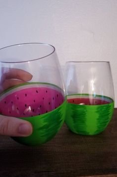 two glasses with watermelon painted on them are being held by someone's hand