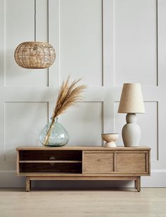 a table with two vases and a lamp on it next to a white wall