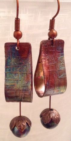 two metal earrings hanging from hooks on a wall