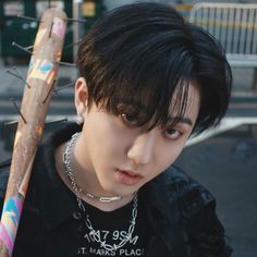 a young man with black hair holding a baseball bat