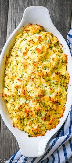 a casserole dish with cheese and broccoli in it on a blue and white towel