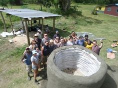 a group of people standing in front of a large cement object on top of a lush green field