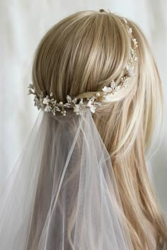 a blonde woman wearing a veil with flowers on her head and hair comb in the shape of a flower