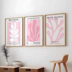 three pink posters hanging on the wall in a living room with two baskets underneath them