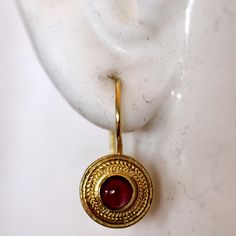 Handcrafted of a tiny disc of filigree thread, this classic Greek design highlights the beauty of a single cabochon garnet. The original Greek earrings are part of the Museum's permanent collection. 14k gold settings. Hinged backs for pierced ears. Size: 7/8 Inches. Elegant Gemstone Ceremonial Earrings, Elegant Ceremonial Gemstone Earrings, Elegant Gold Garnet Cabochon Jewelry, Gold Byzantine Jewelry With Cabochon, Byzantine Gold Jewelry With Cabochon, Byzantine Gold Cabochon Jewelry, Round Cabochon Garnet Jewelry, Round Garnet Cabochon Jewelry, Gold Ruby Round Earrings