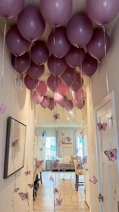 purple and pink balloons are suspended from the ceiling in this hallway decorated with butterfly decorations