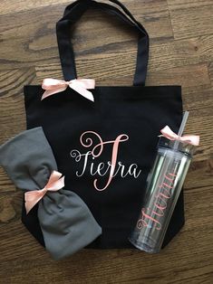 a black tote bag with pink bows and personalized name on it, along with a tumble cup